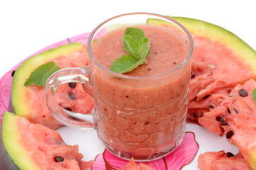 closeup sliced red ripe watermelon with juice and mint in the plate isolated on white background.