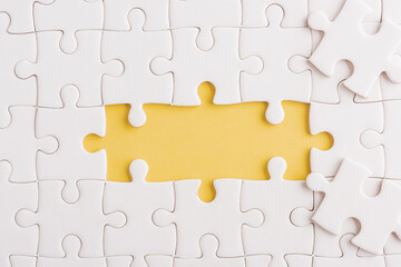 Top view flat lay of paper plain white jigsaw puzzle game texture incomplete or missing piece, studio shot on a yellow background, quiz calculation concept