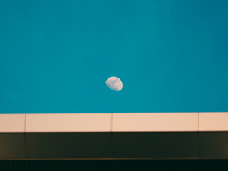 Moon in daylight afternoon warm sunlight on top of industrial building rooftop