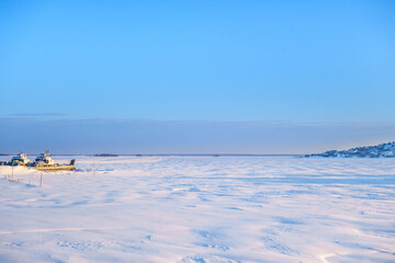 Panorama of frozen river on sunny winter day. On left side you can see ships remaining in dock. On...