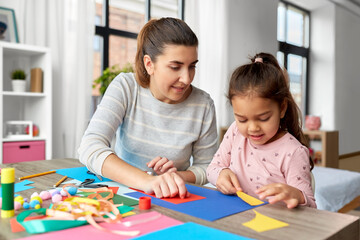 family, art and craft concept - mother spending time with her little daughter making applique of...