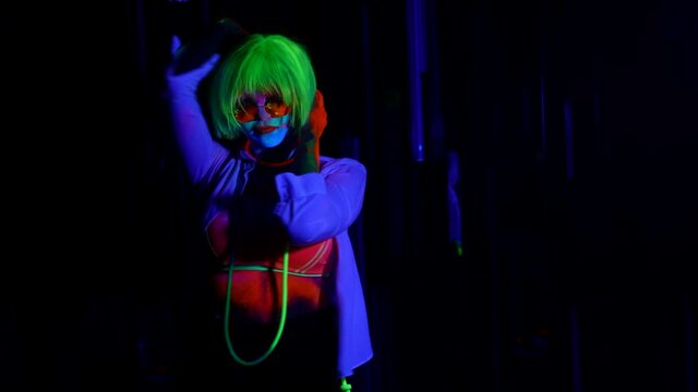 eccentric female guest of nightclub, lady with fluorescent makeup is moving on dark dancefloor