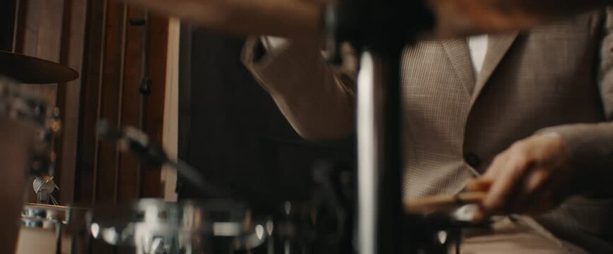 CU Caucasian male wearing suit playing drums during jass band rehearsal in recording studio. Shot with 2x anamorphic lens