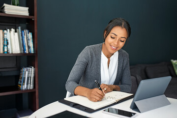 Young woman writing notes while working from home