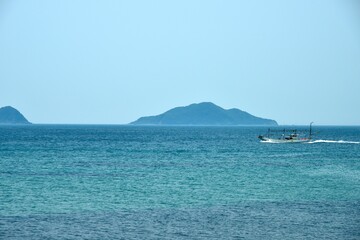 Obraz premium 日本海を帰港する漁船と島の風景