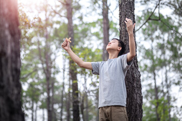 asian Boy hands raised praying with the cross in forest, Focus face, Christian concept.