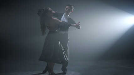 Elegant ballroom couple dancing on stage. Professional dancers performing waltz.