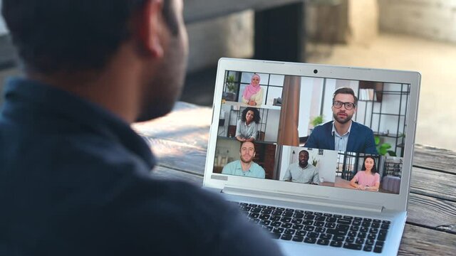 Back view of indian businessman talk with co-workers partners using video call on laptop, discuss work project online, talking with clients, speak on webcam conference on computer, greeting