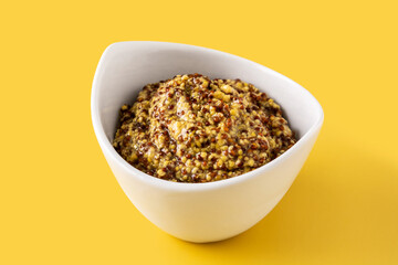 Mustard sauce in white bowl on yellow background