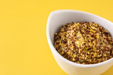 Mustard sauce in white bowl on yellow background