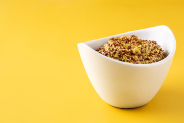 Mustard sauce in white bowl on yellow background
