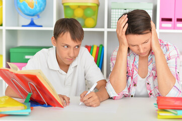 Emotional mother with her son doing homework at home