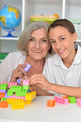 Obraz na płótnie Canvas Smiling boy playing with colorful plastic blocks with grandmother