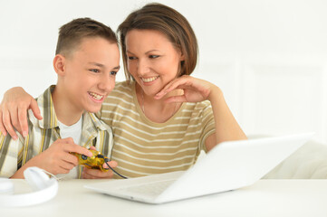 Mother and son using modern laptop at home playing game