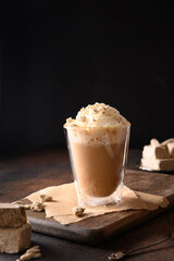 Tasty coffee latte with halva in glass cup for gourmet on dark brown background. Close up.