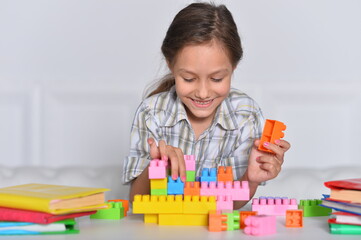 Porait of happy cute little girl playing with cubes
