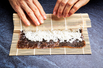 Female chef preparing rice on nori for delicious sushi. Asian food concept
