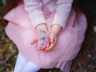 a little girl in a pink dress walking in a lilac garden