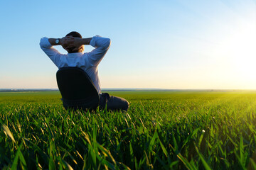 businessman sits in an office chair in a field and rests, freelance and business concept, green...