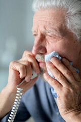 Portrait of sad sick senior man calling doctor