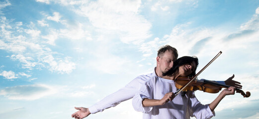 Woman in love with violin. Couple in love. Sensual. Violin. Sky background. Sensual. Happy day. Fashion photo. 
