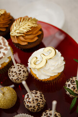 Festive table with sweet treats in the form of cakes and eclairs with custard and chocolate cream. Birthday gilded cupcakes