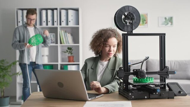 innovative technology, young creative boy and girl print a prototype of a lamp shade on a 3 d printer for home use in the living room