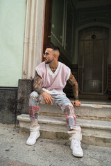 Chico joven guapo tatuado posando en entornos urbanos con ropa a la moda