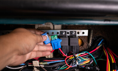 Auto mechanic checking a car fuse box.