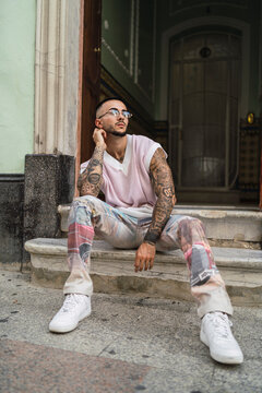 Chico joven guapo tatuado posando en entornos urbanos con ropa a la moda