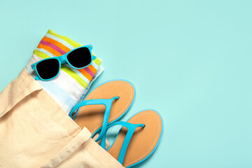 Summer holiday concept.Top view of blue flip flops,beach towel, blue sunglasses and beach bag with...