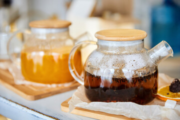 Black tea and Sea buckthorn tea in a transparent glass teapots. Close-up, selective focus