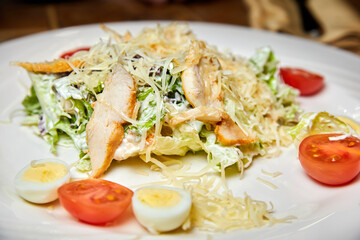 Chicken breast salad with parmesan cheese, eggs and tomatoes. Close-up, selective focus