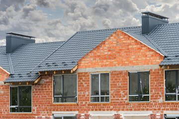 Frame duplex townhouse under construction with metal roof and chimney pipe.