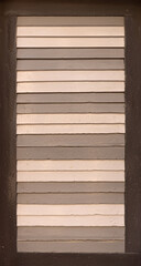 Alter Fensterladen aus Holz mit Lamellen in Nahaufnahme, gestrichen mit Muster in verschiedenen Brauntönen