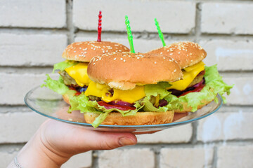 Burger with beef, cheese and lettuce on a brick wall background. Outdoor recreation. Close-up, selective focus. High quality photo