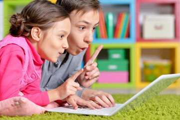 Happy brother and sister using modern laptop