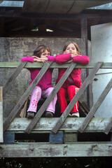 Obraz na płótnie Canvas Zwei Kinder Mädchen sitzen an der Brüstung vom Baumhaus
