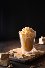 Tasty coffee latte with halva garnish caramel syrup for gourmet on dark brown background. Vertical orientation.