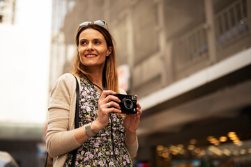 Attractive tourist with a camera. Beautiful woman with camera taking photos of beautiful location...