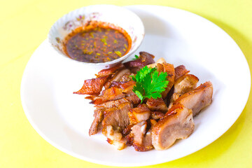 Grilled pork mask was marinated with minced coriander root, black pepper and garlic and served with Thai spicy sauce (Jaew sauce).