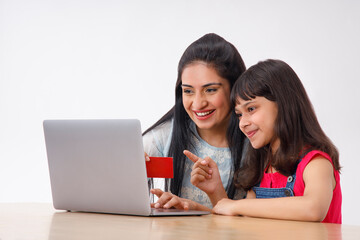 Obraz premium A HAPPY MOTHER AND DAUGHTER DOING ONLINE TRANSACTION 