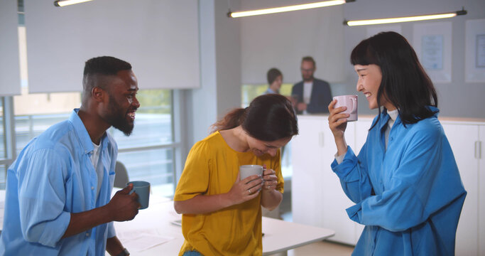 Multiethnic colleagues on break drinking coffee chatting in modern office