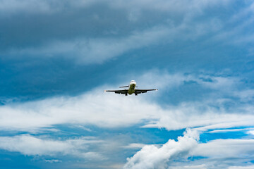 Fototapeta na wymiar Passenger airplane landing against blue cloudy sky.
