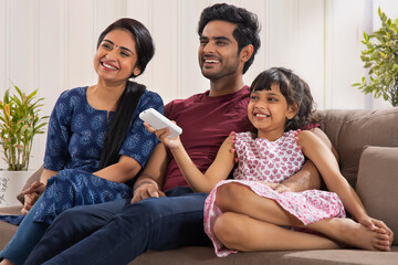 A HAPPY COUPLE AND THEIR DAUGHTER SITTING TOGETHER AND ENJOYING TIME AT HOME	