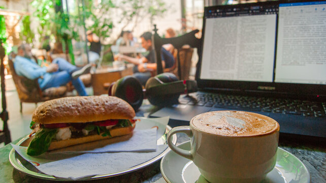 Midday work break with a great sandwich and cappuccino. Background with cafe design.