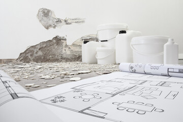 house renovation and plan concept. Blue print project draw. Buckets and jerry can products for painting and plastering on white wall under construction with rubble, copy space background