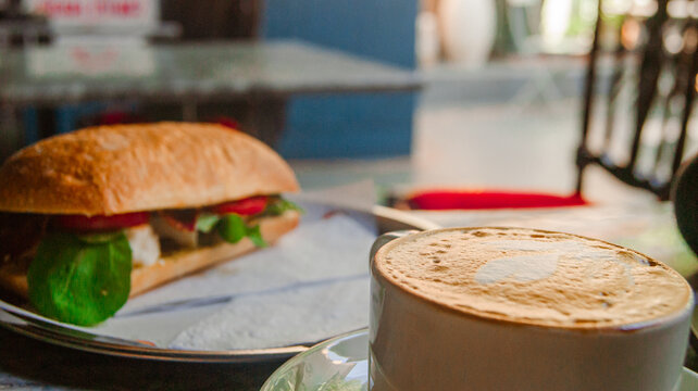 Midday work break with a great sandwich and cappuccino. Background with cafe design.