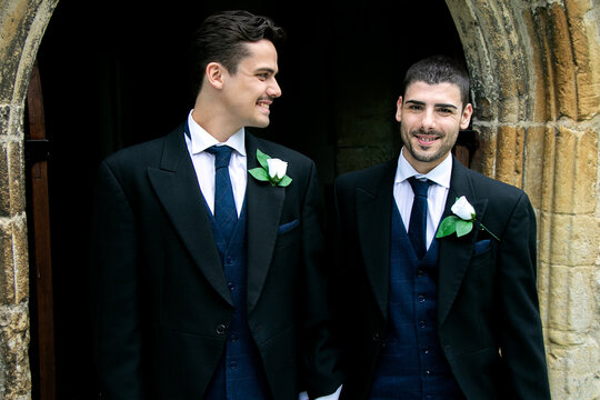 Smiling gay grooms dressed in suits leaving church after getting married