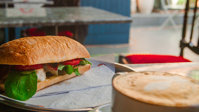 Midday work break with a great sandwich and cappuccino. Background with cafe design.